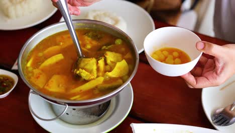 ladling soup into a bowl at a table