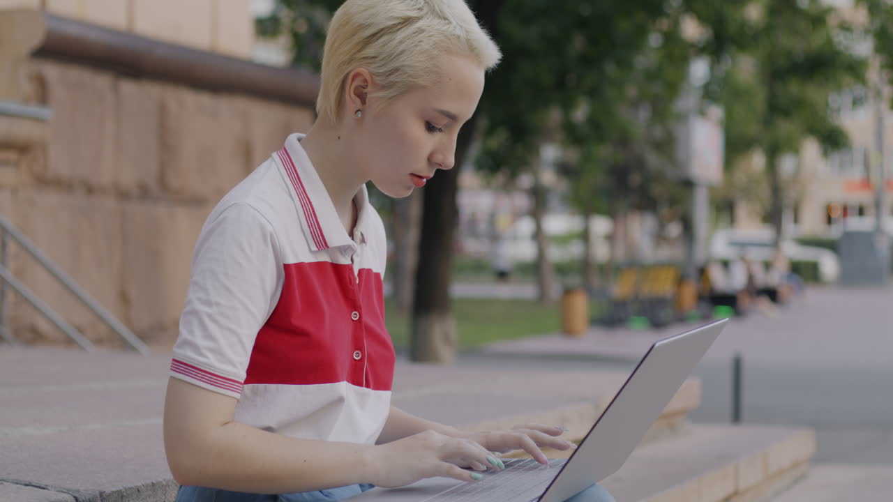 mujer joven trabajando en una computadora portátil en las escaleras de la ciudad