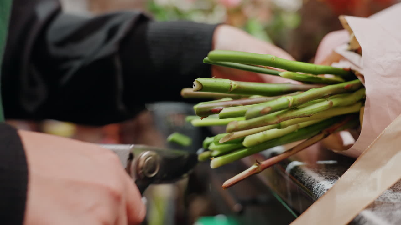 White florist cutting stems with shears, trimming excess for even arrangement, closeup hands and vibrant green stems, fast precise motion, busy shop background with tools and ribbons, workflow focus