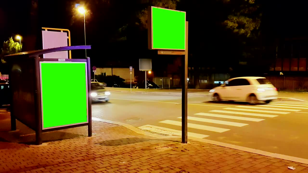 Billboard with a chroma key green screen on a traffic city night street, light night, advertisement
