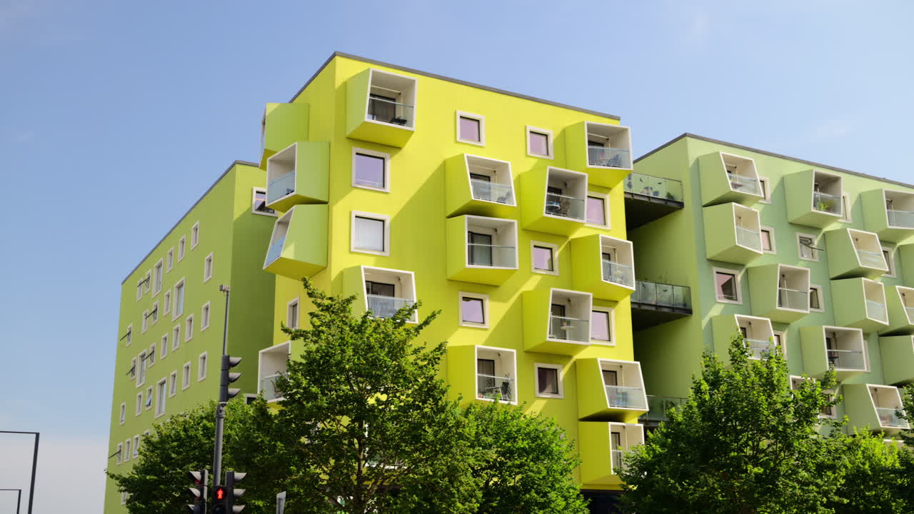 Modern residential buildings showing striking lime green and pastel green facades with geometric cube balconies. Copenhagen, Denmark