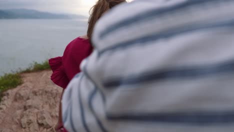 loving couple kissing on rocky cliff near sea