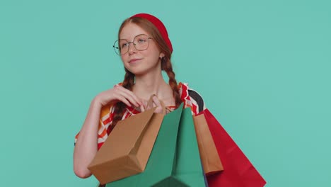 chica pelirroja mostrando bolsas de compras, anuncios de descuentos, sonriendo mirando asombrado con los precios bajos