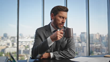 office manager reading documents at panoramic window. calm man drinking coffee