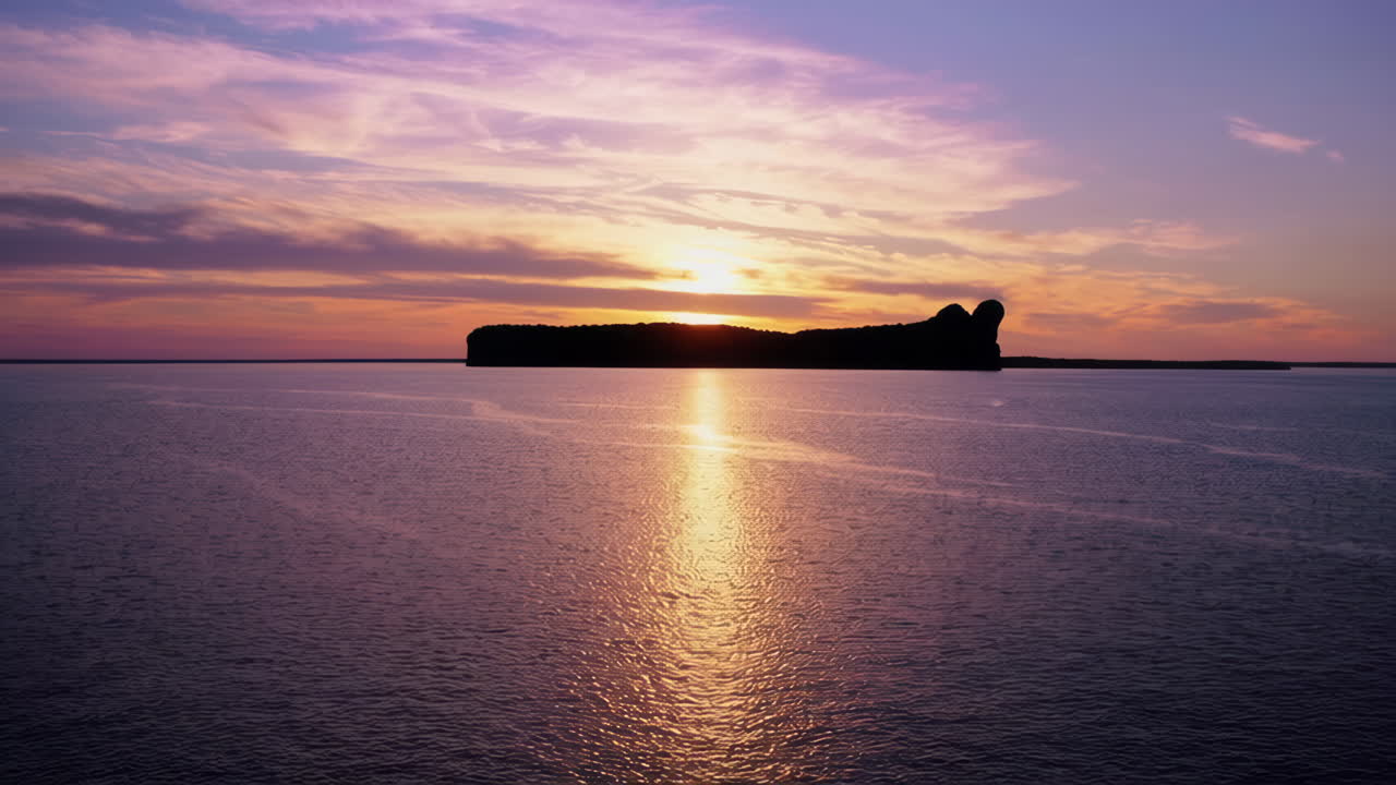 Vibrant Sunset over Water with Silhouetted Landmass