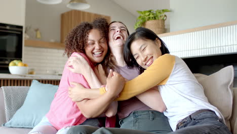 Hugging and laughing, three women friends enjoying time together at home