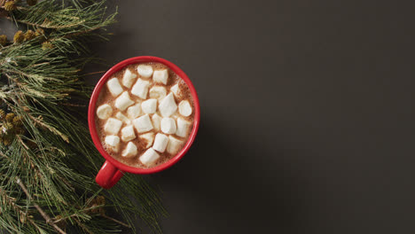 video of cup of hot chocolate with marshmallows and warm blanket over black background