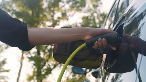 Hand-putting-a-charger-in-an-electric-car,-close-up-low-angle-shot