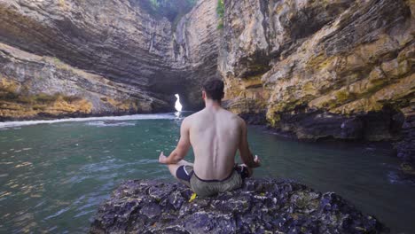 nature lover young man meditating in seaside cave.