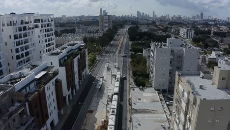 New-light-rail-train-driving-through-Tel-Aviv-city-center,-aerial-establishing-shot