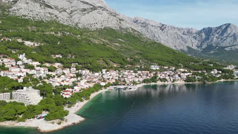 Brela-Kroatien-Kleine-Küstenstadt-Drohne-Schwenk-Hoch-Pov-Blau-Meer-Grün-Bewaldet-Hang