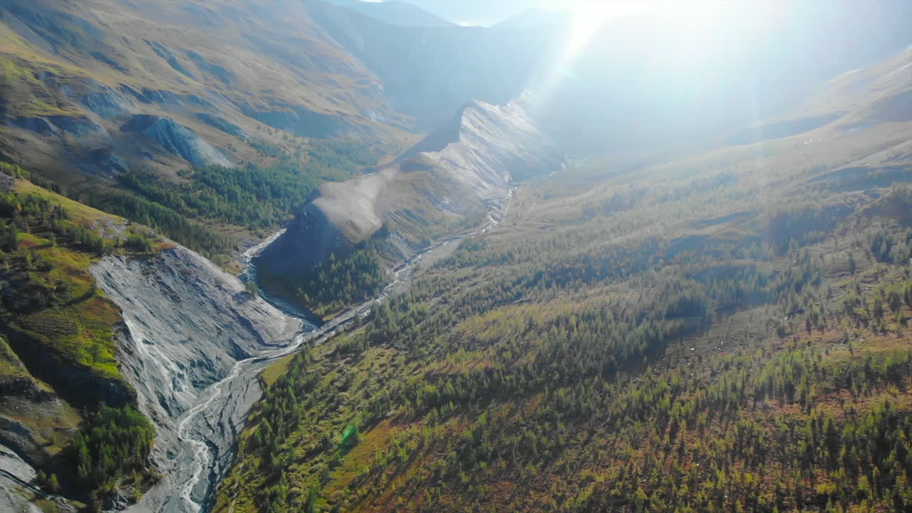 Aerial View of a Sunlit Mountain Valley with River and Forests