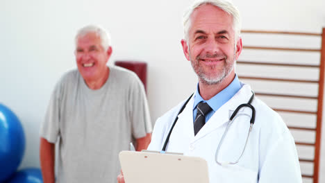 un médico sonriente leyendo desde el portapapeles