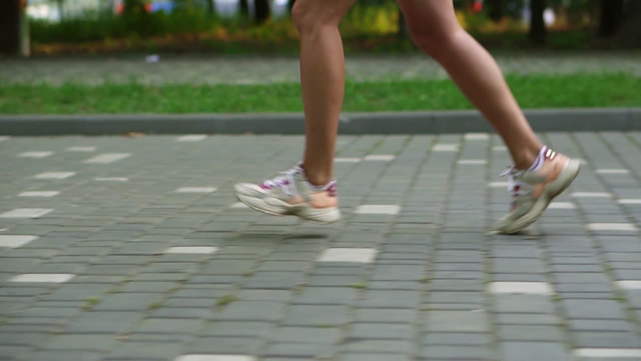 Close Up of female athlete's feet running at the park. Fitness woman jogging outdoors. Exercising on park pavement. Healthy