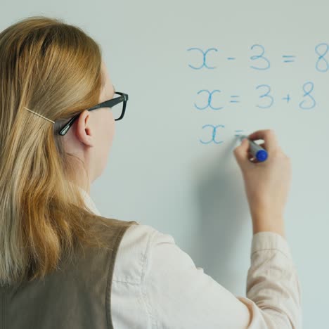 vista trasera de un profesor resolviendo una ecuación en álgebra