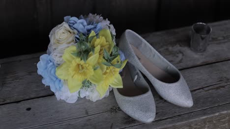 brides blue, white and yellow bouquet with her silver heels laid out as a flat lay on a wooden bench