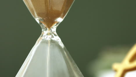 close up of the centre of an hourglass as the sand flows through it in slow motion