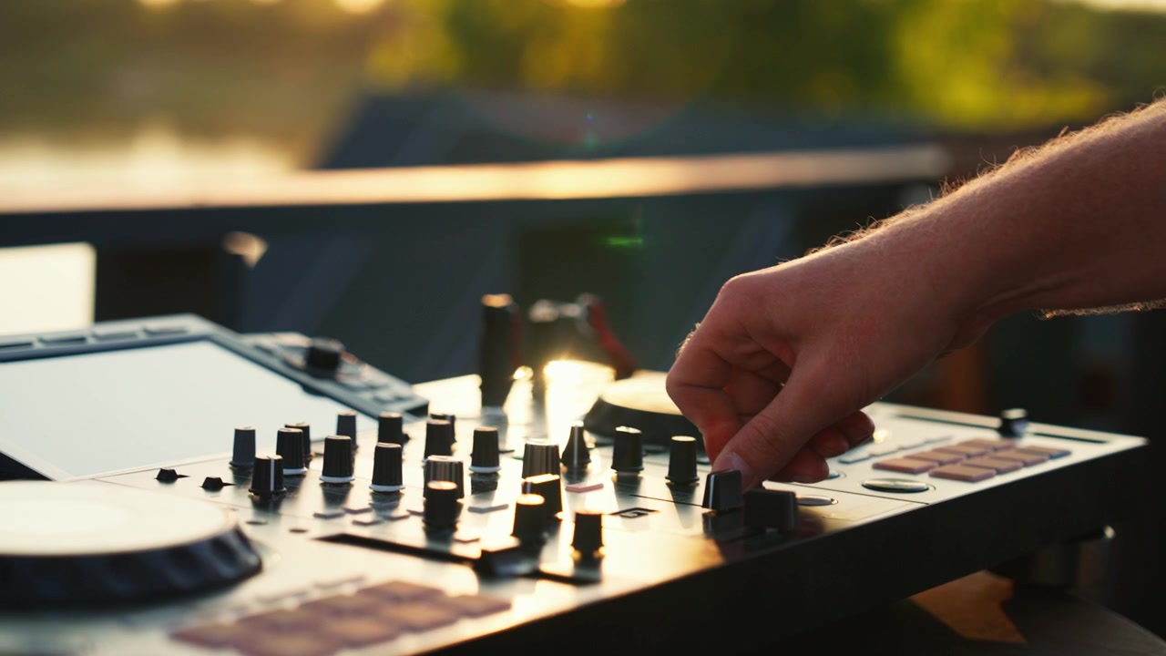 DJ Adjusting Audio Levels on Mixing Console at Sunset