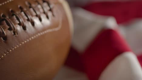 primer plano de la persona recogiendo el fútbol americano con la bandera de rayas y estrellas en el fondo 1