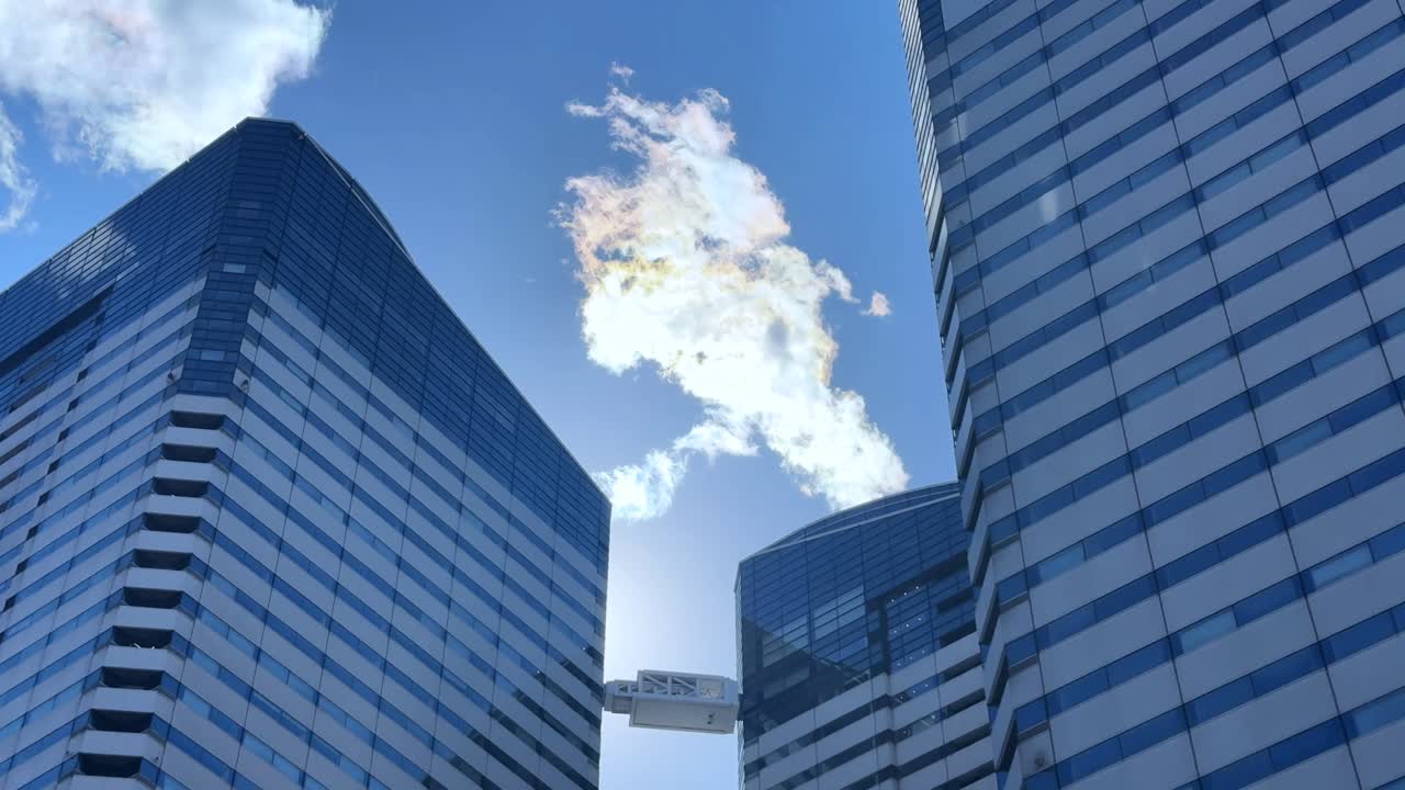 Tall buildings under blue sky in Tokyo, with reflections on the glass windows