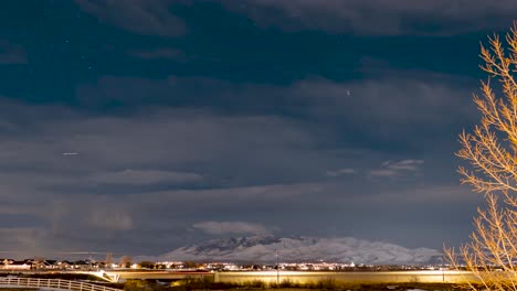 estrellas cruzando el cielo mientras sopla una tormenta de nieve de invierno - lapso de tiempo nocturno sobre un paisaje suburbano