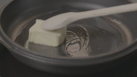 stirring butter around a cooking pan in slowmotion while it melts and becomes fluid log