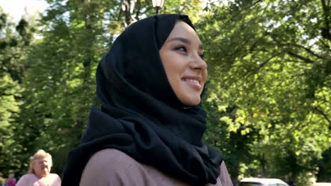 young happy muslim girl in hijab is smiling and watching at university in daytime in summer, religious concept, studying concept