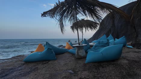 blue lounge chairs with yellow pillows on sandy beach with palm trees, summer night