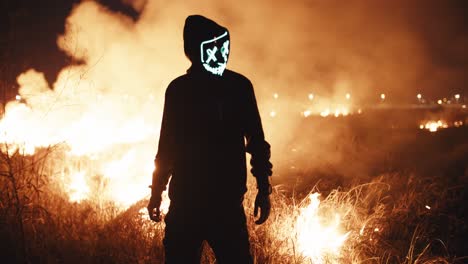 person in glowing mask amidst a fire