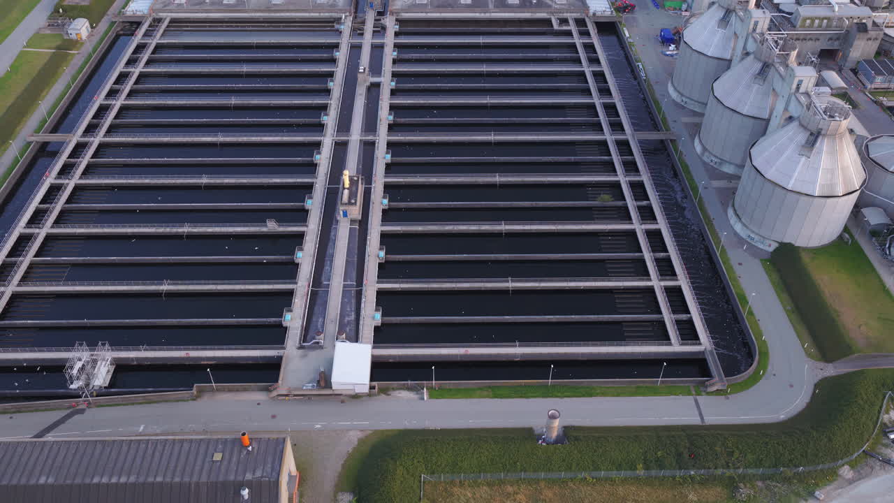 Aerial drone view of the wastewater treatment facility with long water basins and processing structures in Copenhagen, Denmark