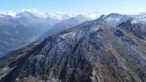 Una-Gran-Roca-Frente-A-Montañas-Nevadas-En-Los-Alpes-Suizos,-Drones-Aéreos