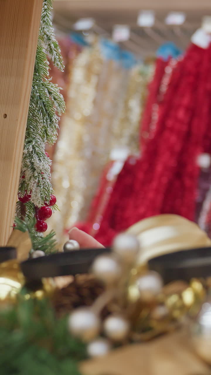 Elegant lady in white sweater carefully touches festive decor in a well-lit Christmas decoration shop, shelves filled with colorful tinsel, ornaments, and holiday items
