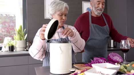 senior biracial couple cleaning waste in kitchen, unaltered, in slow motion