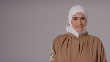 studio-porträt einer lächelnden muslimischen frau, die einen hijab trägt, gegen einen einfachen hintergrund 3