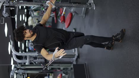 Young-man-exercising-on-multi-station-at-gym-for-arm-and-shoulders-muscles,-slow-motion