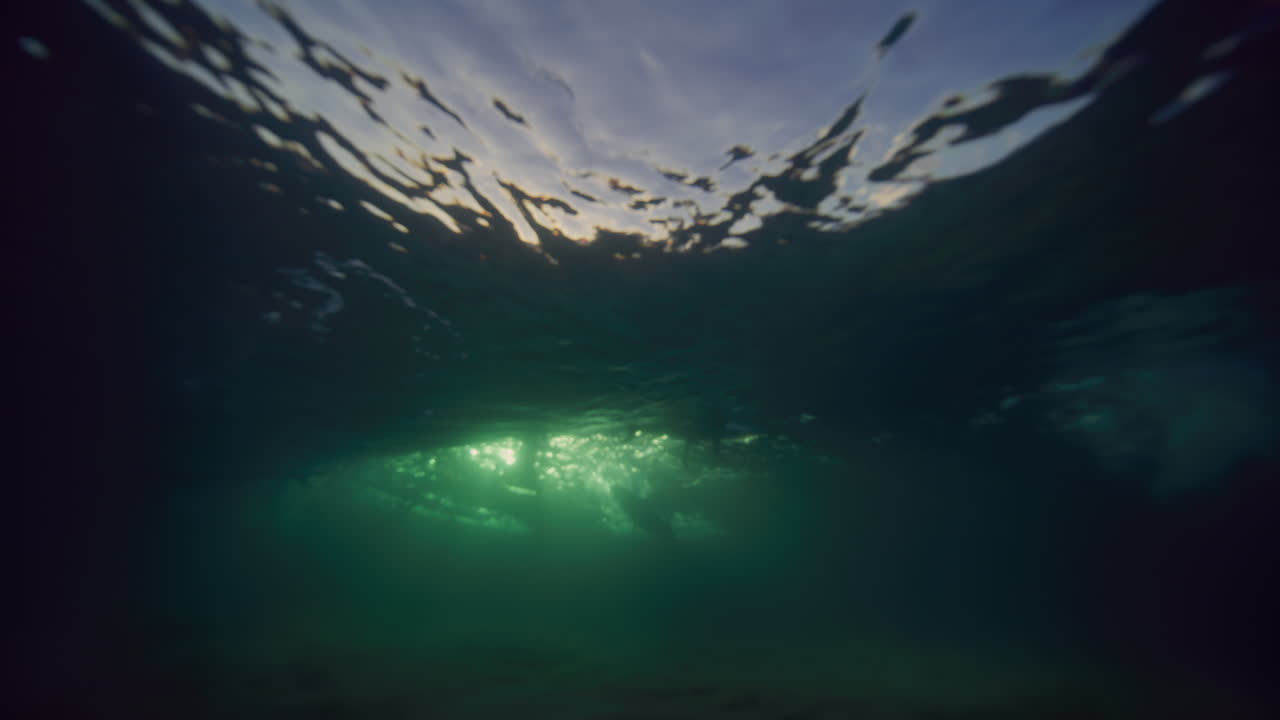 brillantes rayos dorados de luz revelan detrás de la textura de las olas que rompen bajo el agua