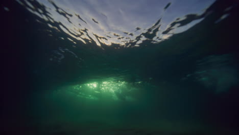 Los-Brillantes-Rayos-Dorados-De-Luz-Se-Revelan-Detrás-De-La-Textura-De-Las-Olas-Rompientes-Bajo-El-Agua.