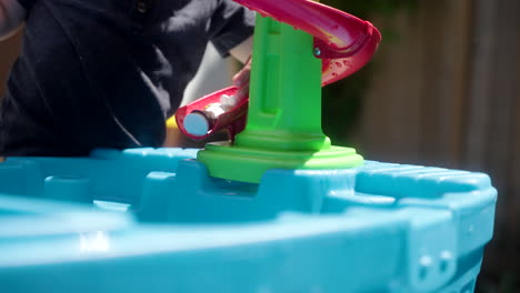 child pushing his toys down a toy water slide