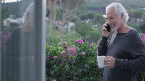 senior man with coffee cup talking on mobile phone 4k