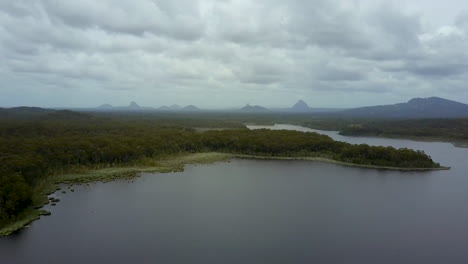 Aerial-shot-over-lake-with-mountains-in-the-distance