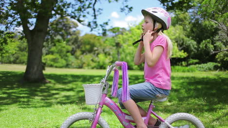 girl puts on a cycling helmet and holds the handle bars