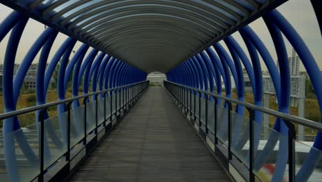 crossing a bridge made of blue metal tubes over the highway on foot