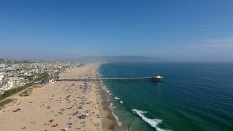 crowded manhattan beach with pier at summer in california, usa. - aerial