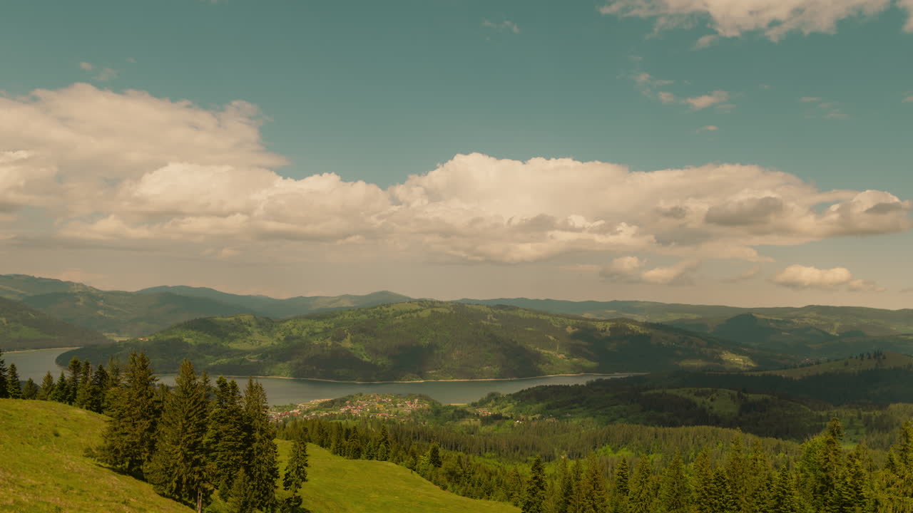 Timelapse showing an accumulation lake surrounded by green, forested mountains, partly cloudy