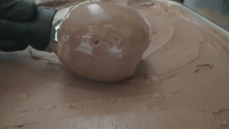 close-up slow motion shot of a spoon scooping a rich, creamy ball of chocolate ice cream. the luscious dark texture and smooth surface highlight the indulgent nature of this frozen dessert