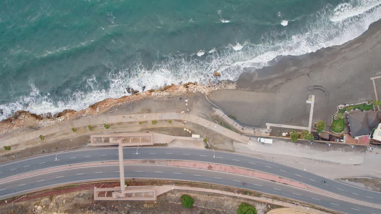 toma aérea de arriba hacia abajo de los coches en la carretera costera y la playa del candado en málaga durante el día soleado