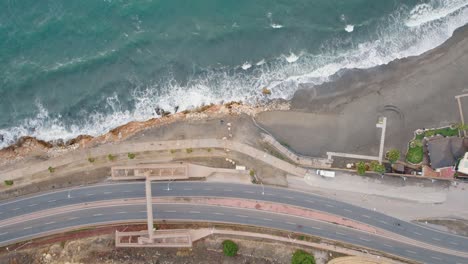 aerial top down shot of cars on coastal road and candado beach in malaga during sunny day