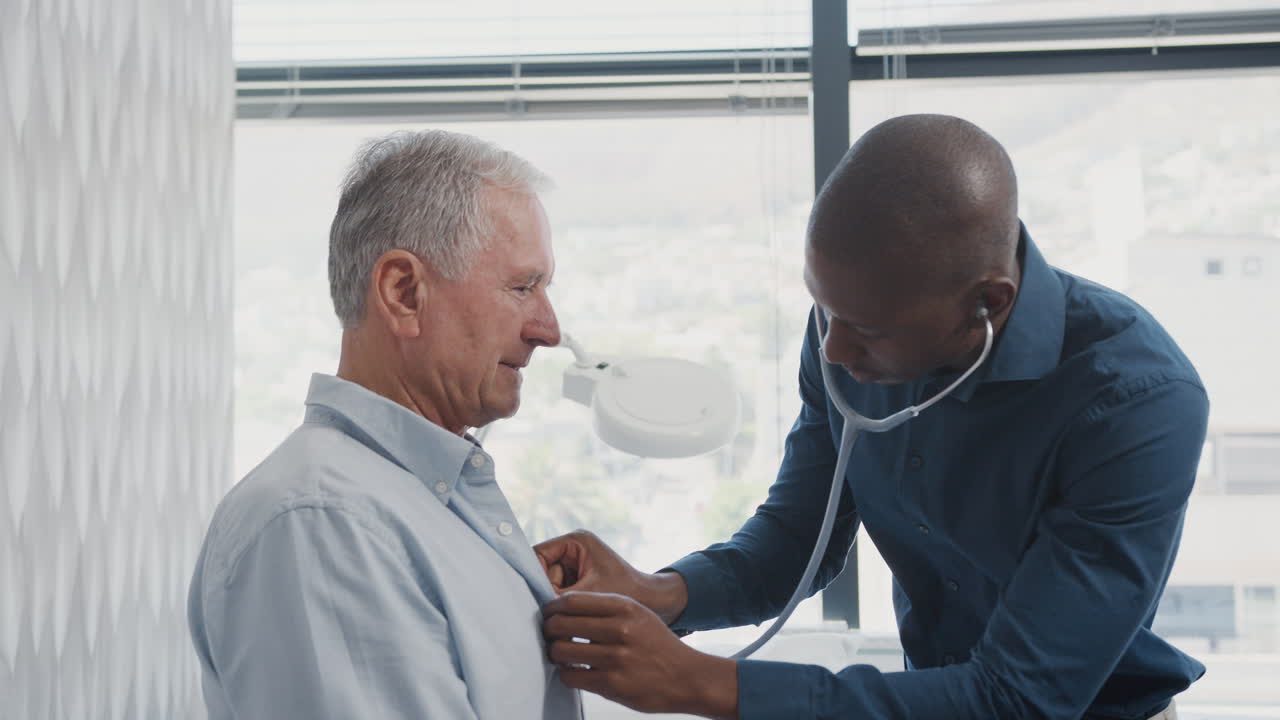 médico escuchando a un paciente masculino anciano respirando con estetoscopio durante un examen médico en la oficina