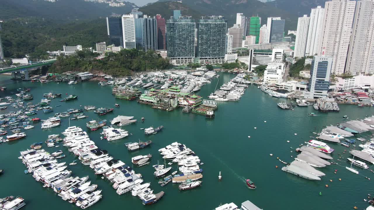 Hong Kong marina and Typhoon shelter with the famous Jumbo floating restaurant, skyscrapers and hundreds of small boats on a clear Summer day, Aerial pull up view.