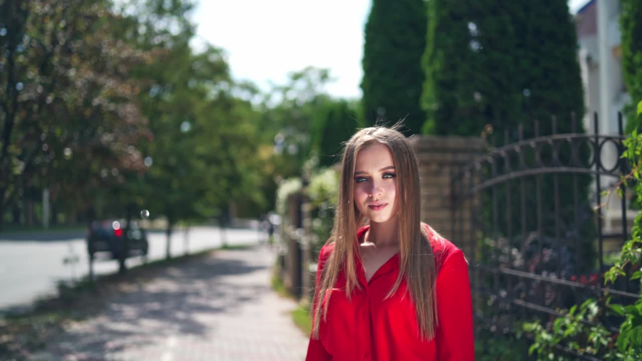 Woman walks down the street. Young smiling woman look at camera, walking in the city streets